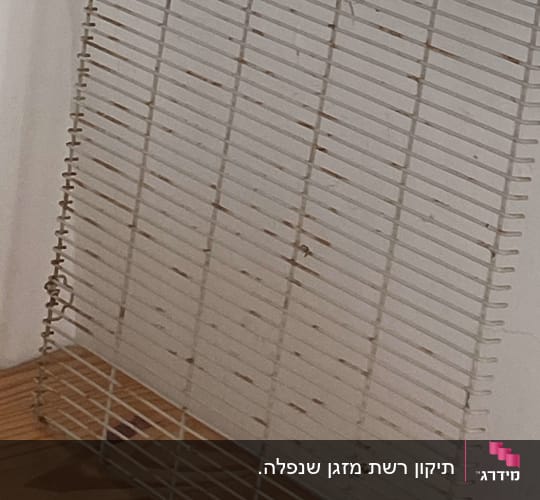רשת מתכת על שולחן עץ ליד קיר לבן